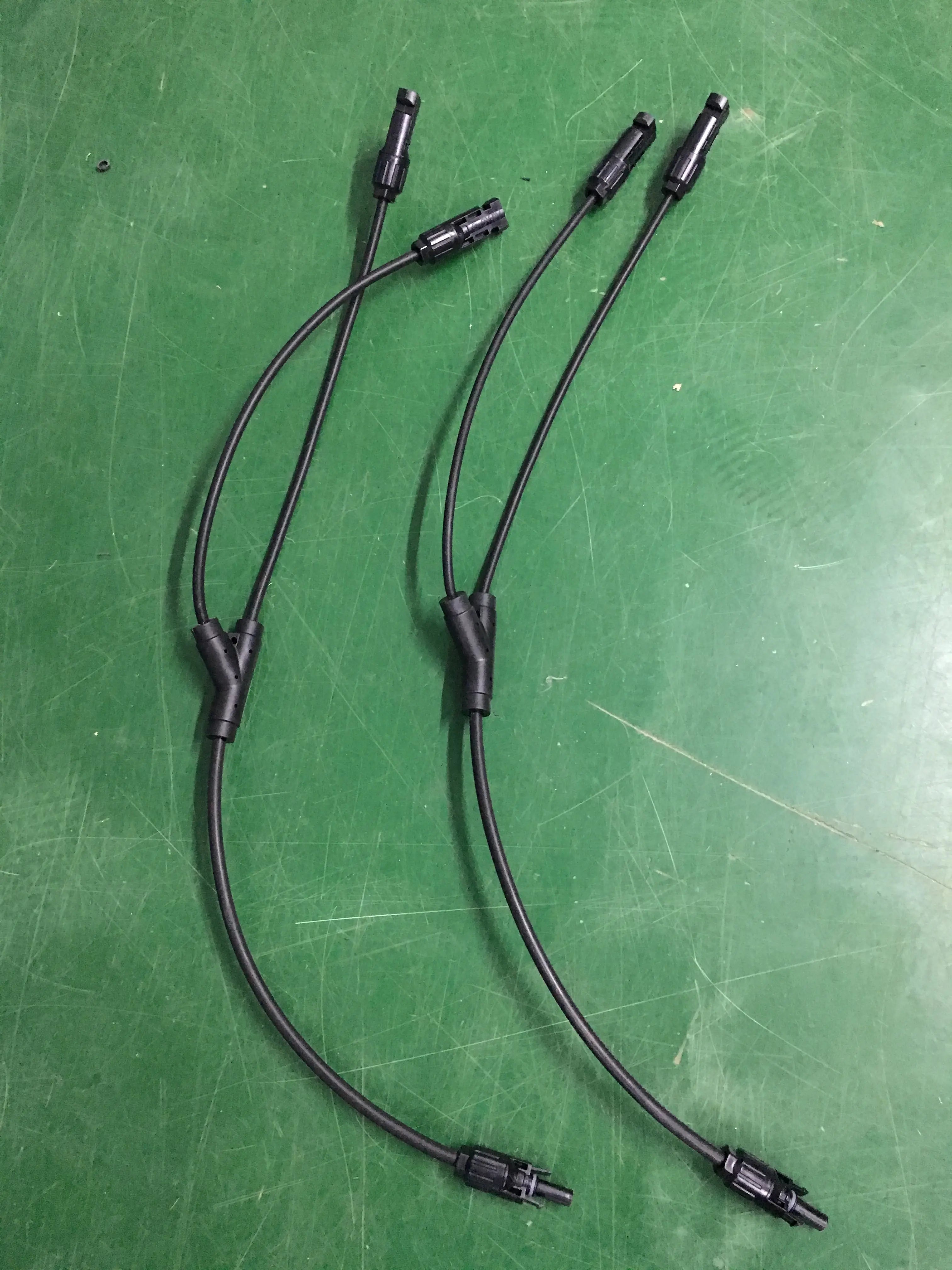 Two PVconnectorpro CM21-A 1000V DC solar Y-branch connectors on green work surface, waterproof IP67, TUV and UL certified.